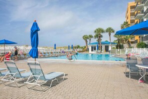 A pool area with lounge chairs and umbrellas, surrounded by a building with balconies. - Beachfront, 3rd-floor condo with pool, hot tub, ocean view & fast WiFi (Fort Walton Beach)