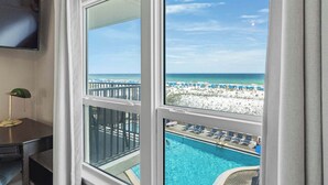 Ein Zimmer mit großem Fenster mit Blick auf Pool und Strand.