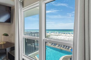 Una habitación con un amplio ventanal con vistas a una piscina y una playa.