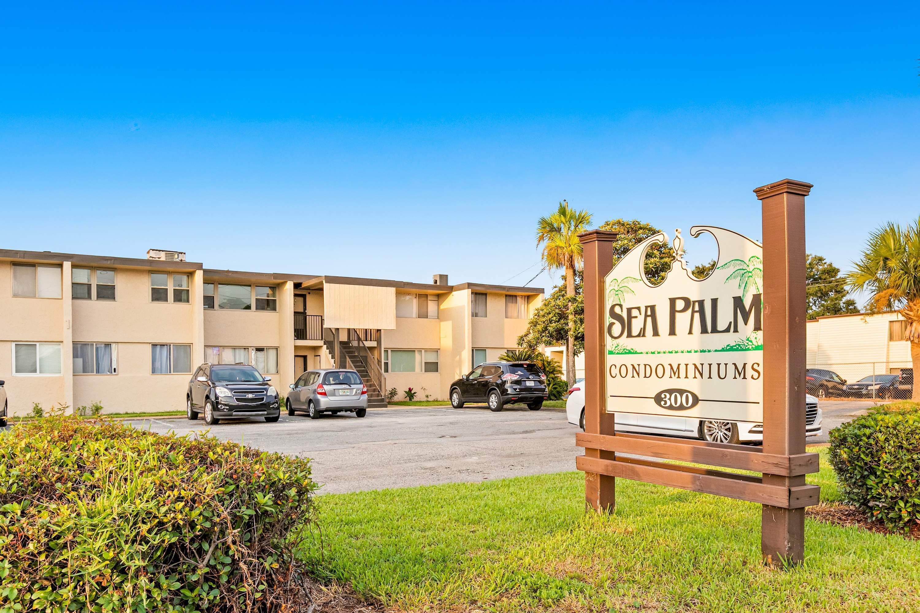Señal de Sea Palm Condominiums con vista despejada del exterior del edificio y coches aparcados.