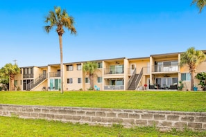 Un hotel de varios pisos con balcones, piscina y palmeras.