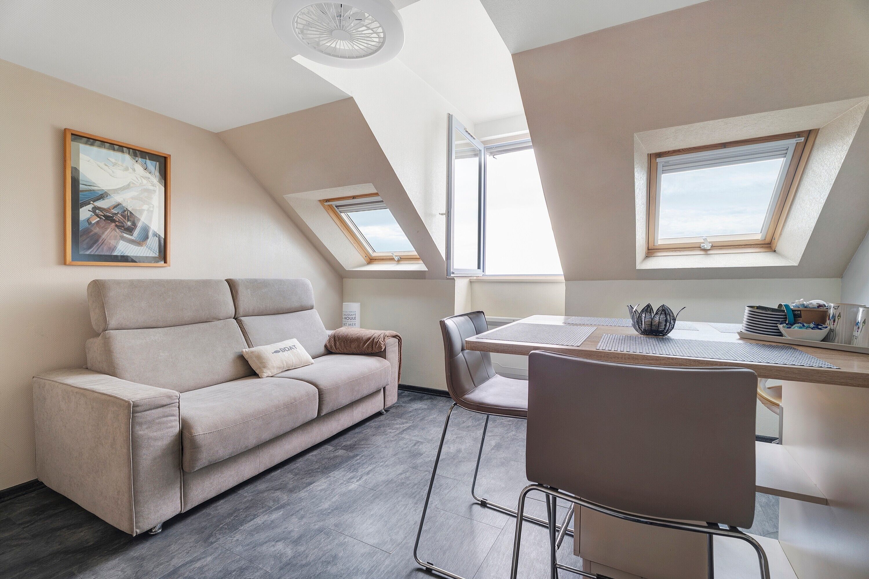 Un moderno loft con sofá, mesa de comedor, sillas y tragaluces.