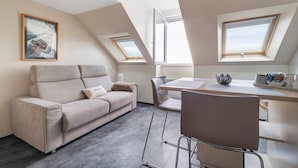 Un moderno loft con sofá, mesa de comedor, sillas y tragaluces.