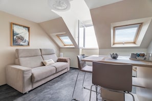 A modern loft apartment with a sofa, dining table, chairs, and skylights. - Duplex Apartment Facing the Sea with Mont Saint Michel View (Cancale)