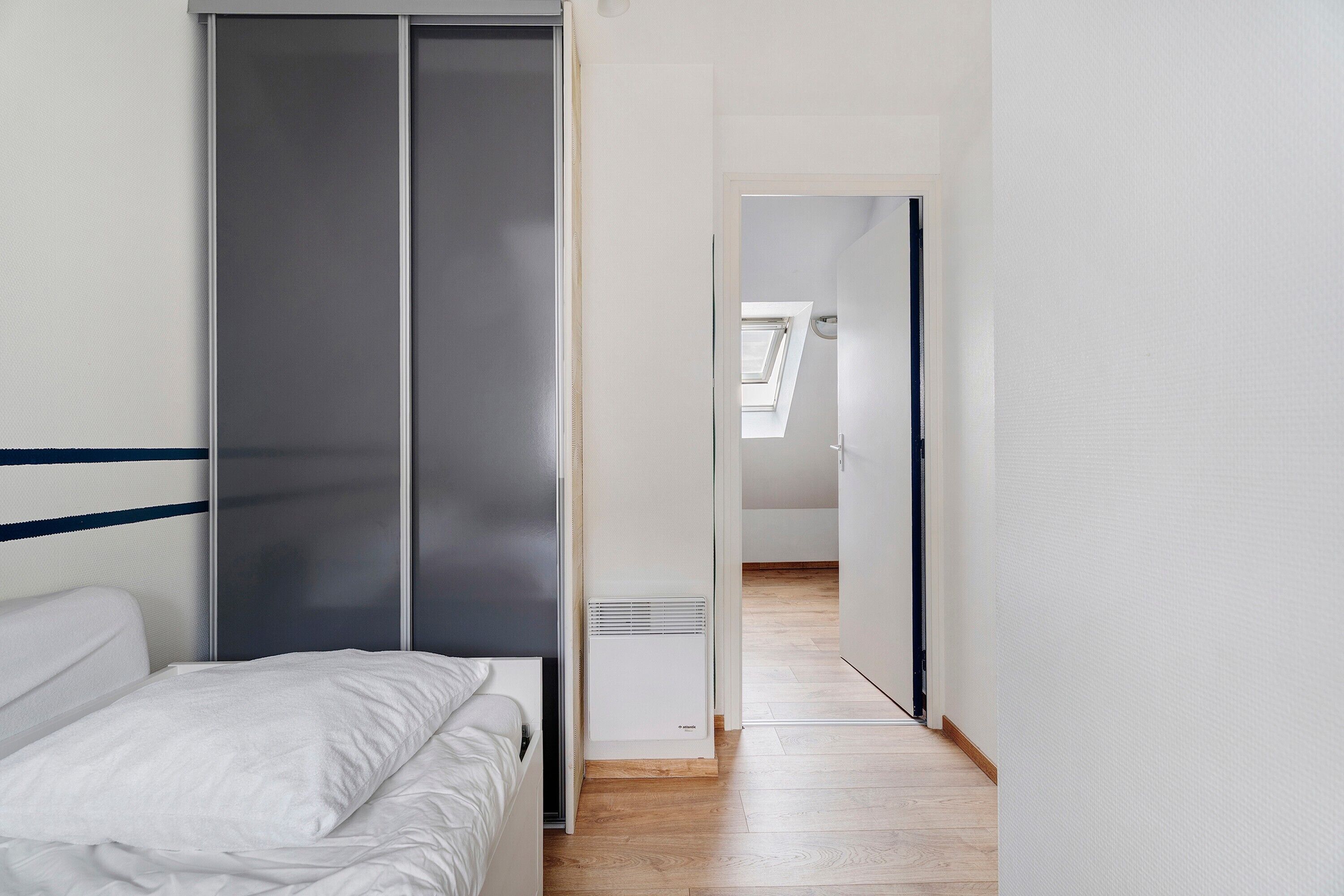 A bedroom with a bed, a wardrobe, and a heater.