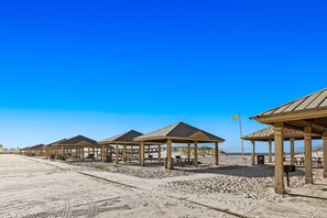 Des cabanes de plage équipées de tables de pique-nique et d’un drapeau.