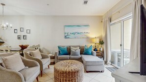 Un salon comprenant un canapé, un pouf et un tableau accroché au mur.
