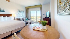 A hotel room with a bed, a dining table, a TV, and a window with a view. - Luxurious condo near downtown, beach, & golf with pools & tennis (Miramar Beach)