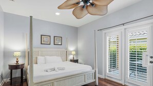 A four-poster bed with white bedding, two bedside lamps, and a ceiling fan. - Destin Mojo (Miramar Beach)