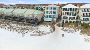 A beachfront hotel with multiple balconies, a sandy beach, and a staircase leading to the beach. - Destin Mojo (Miramar Beach)