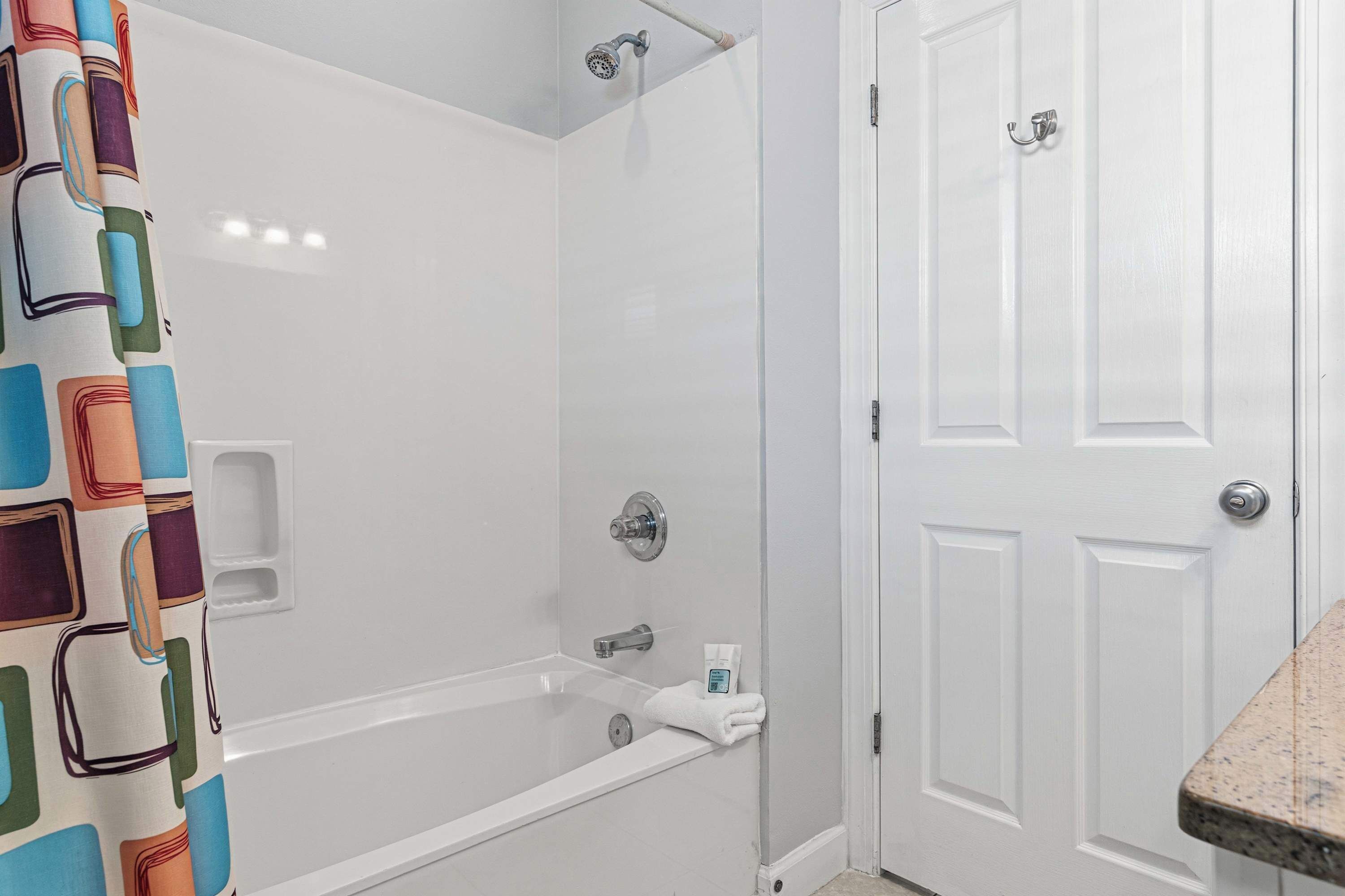 Une salle de bain avec une douche, une baignoire, une porte blanche et un porte-serviettes.