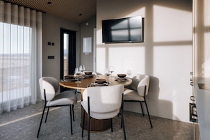 Un comedor moderno con una mesa redonda, seis sillas y un televisor de pantalla plana montado en la pared.