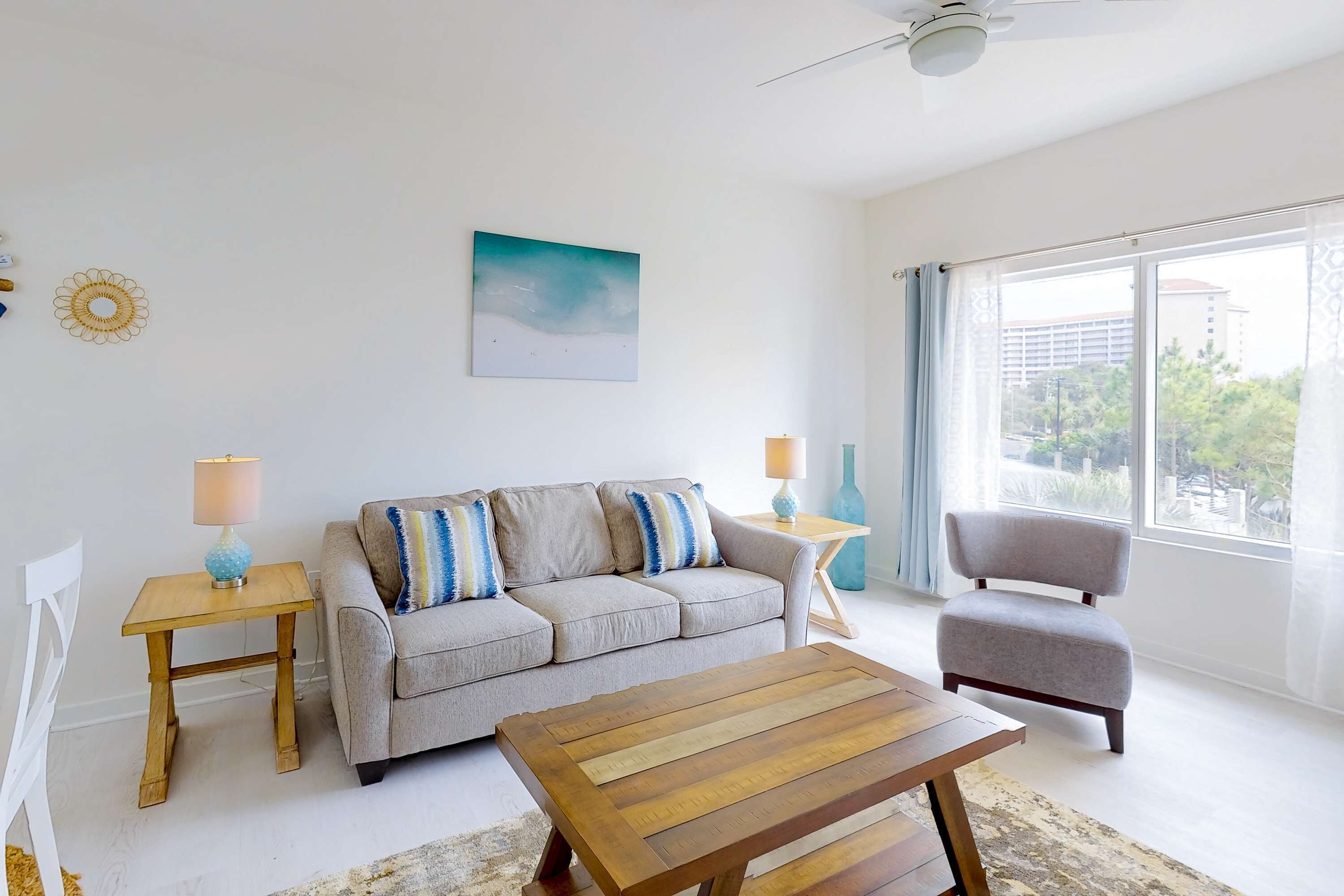 A modern living room with a sofa, a coffee table, a chair, and a large window with a view.