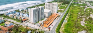 Vista aérea de uma área urbana costeira com edifícios altos, uma estrada e uma praia.
