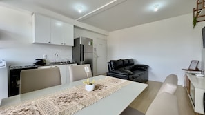 A modern kitchen with white cabinets, a black refrigerator, and a dining area with a table and chairs.