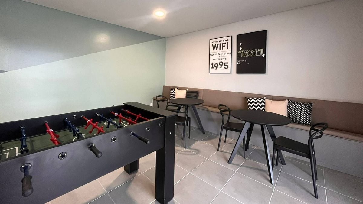 Quarto moderno com mesa de pebolim, um sofá e duas mesinhas.