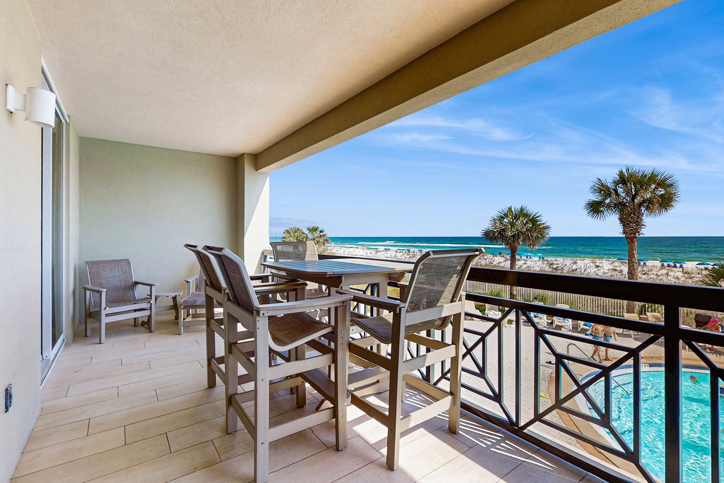 A balcony with a view of the ocean and a pool.