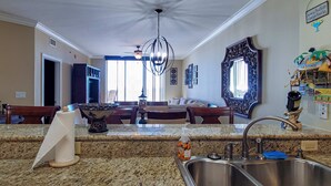 A kitchen with granite countertops, stainless steel sink, and a ceiling fan. - Gorgeous beachfront condo, private balcony, shared pool and beach access (Fort Walton Beach)