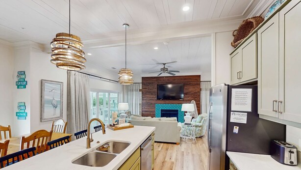 A modern kitchen with a central island, wooden flooring, and a built-in TV. - Spacious home with private pool & full kitchen, close to beach (St. George Island)
