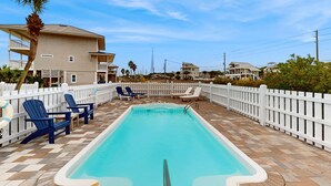 A rectangular pool with a white deck, surrounded by a white picket fence, and blue Adirondack chairs. - Spacious home with private pool & full kitchen, close to beach (St. George Island)