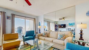 Amplia sala de estar con sofá, sillones y una mesa de centro. Una ventana grande ofrece vistas al exterior.