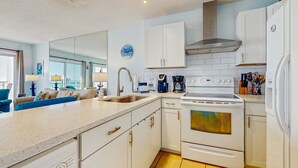 Una cocina moderna con armarios blancos, una campana extractora de acero inoxidable, un horno empotrado y un lavavajillas.