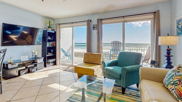 Un salón amplio con un televisor grande, asientos cómodos, un balcón con vistas y un ventilador de techo moderno.