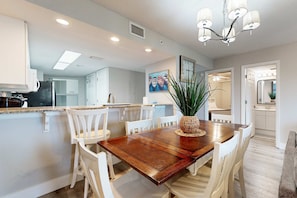 Una cocina moderna con armarios blancos, una mesa de comedor de madera y un candelabro.