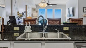 Una cocina con un lavamanos de acero inoxidable, una lámpara de araña y un ventilador de techo.