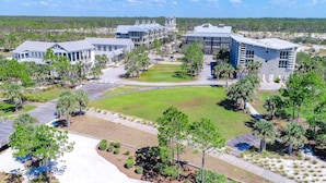 A campus-style building complex with multiple buildings, a central lawn, and surrounding landscaped areas. - 2 dog-friendly beach homes with on-site pool, shopping, dining, AC, & WD (Port St. Joe)