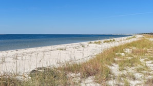 A beach with clear blue water and white sand, featuring dunes and sparse vegetation. - 2 dog-friendly beach homes with on-site pool, shopping, dining, AC, & WD (Port St. Joe)