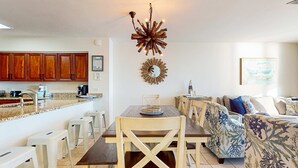 Una cocina moderna con armarios de madera, una mesa de comedor con sillas y una lámpara de araña original.