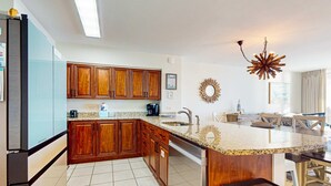 Una cocina moderna con armarios de madera, encimera de granito y lavavajillas integrado.