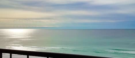 A view of the ocean from a balcony with a railing.