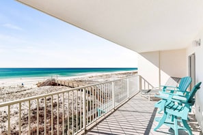 A balcony with a view of a beach and ocean. There are two blue chairs and a white railing. - Gulf Dunes 313 - Gulf-front condo with outdoor pool & tennis - short drive to entertainment (Fort Walton Beach)