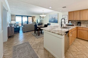A modern kitchen with granite countertops, wooden cabinets, and a dining area with a table and chairs. - Gorgeous coastal condo with shared pool and easy beach access (Miramar Beach)