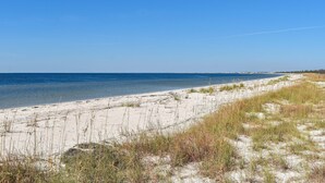 En strand med kristallklart blått vatten och vit sand.