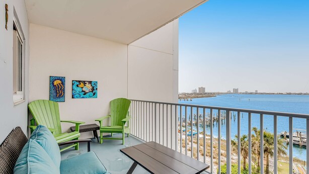 Ein Balkon mit Blick auf das Meer, ein grüner Sessel, ein blaues Sofa und zwei Kunstwerke an der Wand.