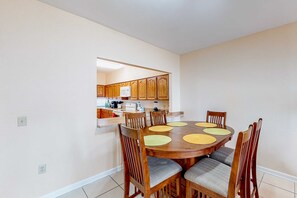 A dining area with a round wooden table surrounded by six chairs, each with a cushioned seat.