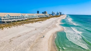 A beachfront hotel with a long, continuous structure along the shore, a sandy beach, and the ocean. - Gorgeous Gulf front townhome, Gas grill and beach access (Pensacola Beach)