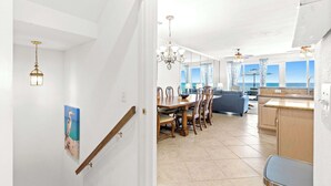 A modern kitchen with a dining area, a view of the sea, and a staircase leading to another level. - Gorgeous Gulf front townhome, Gas grill and beach access (Pensacola Beach)