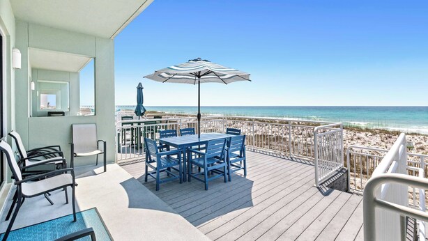 A deck with a table and chairs, a beach view, and a railing. - Gorgeous Gulf front townhome, Gas grill and beach access (Pensacola Beach)