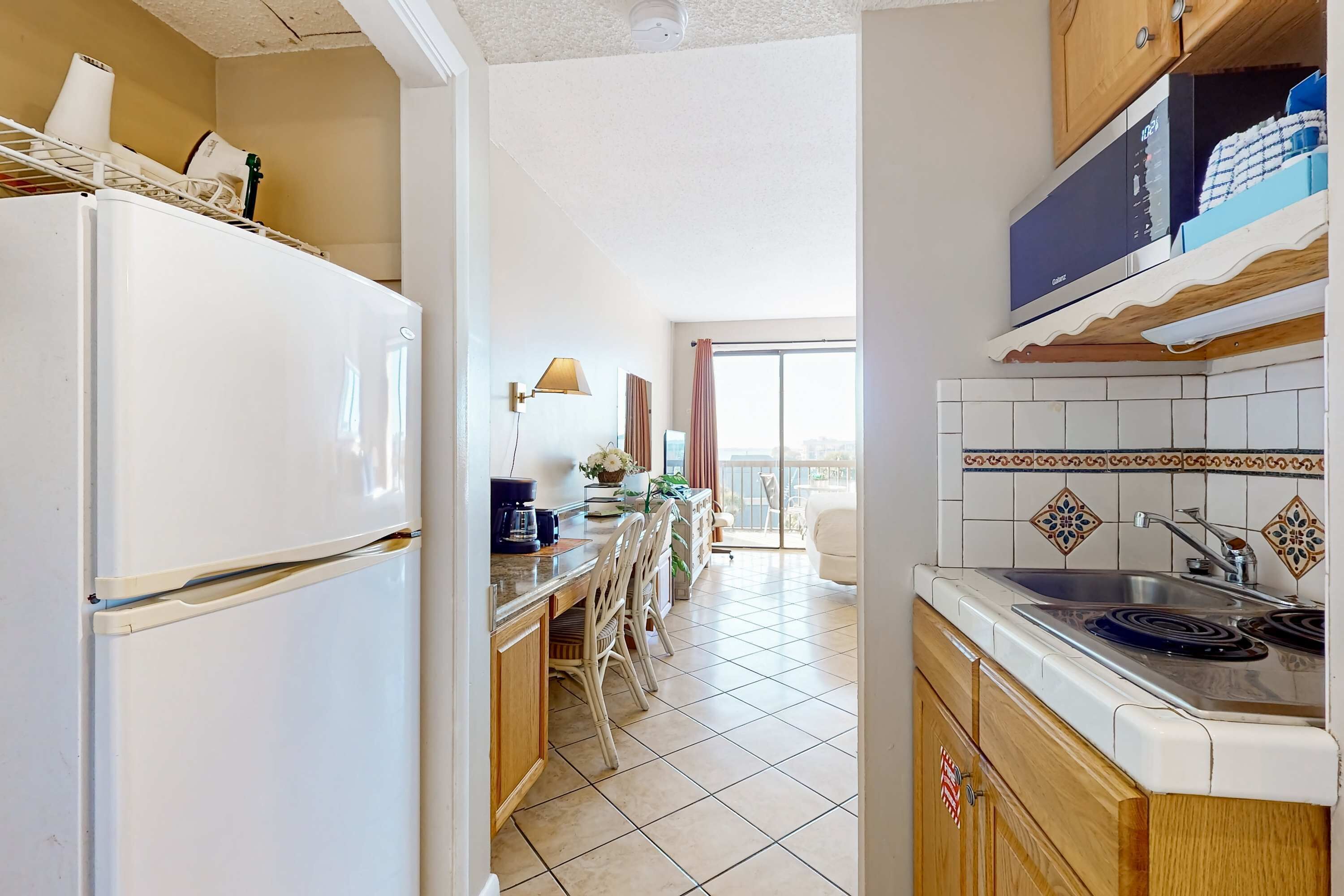 Una cocina equipada con refrigerador, estufa, lavamanos y comedor con sillas y mesa.