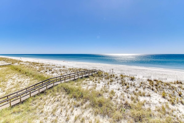 A beach with a wooden boardwalk leading to the shore.