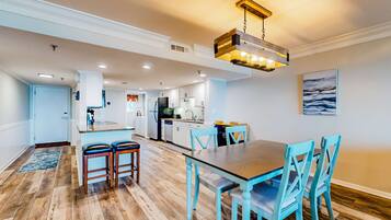 A spacious kitchen with white cabinets, a central island, and a dining area with a wooden table and blue chairs.
