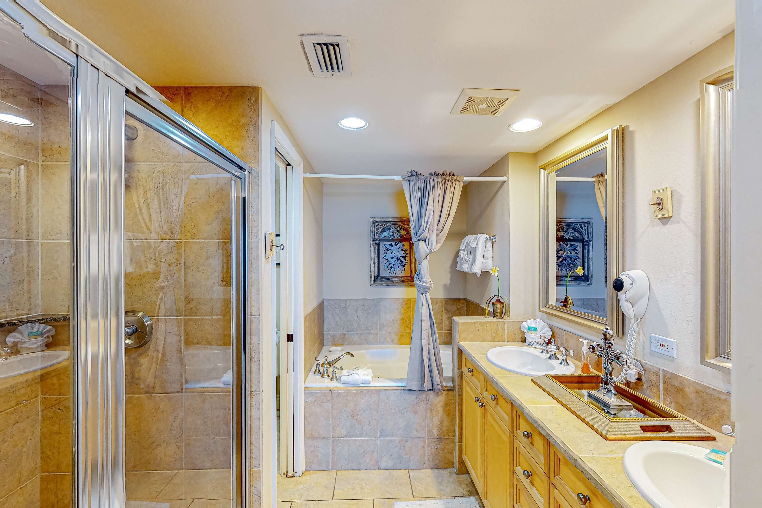 A modern bathroom with a glass shower enclosure, a bathtub, and a vanity with a large mirror.