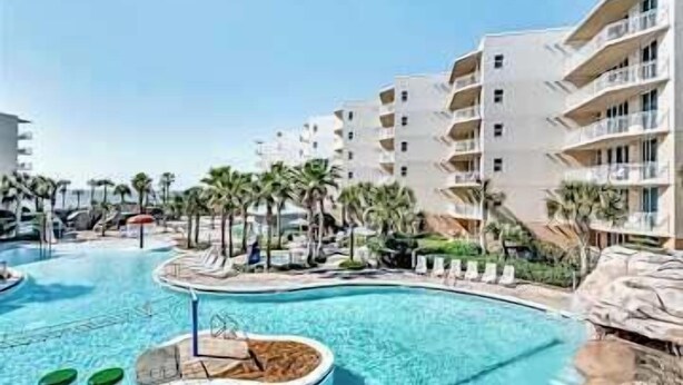 A resort with a swimming pool, palm trees, and multi-story buildings. - Beachview Condo with full kitchen, shared pool and beach access (Fort Walton Beach)