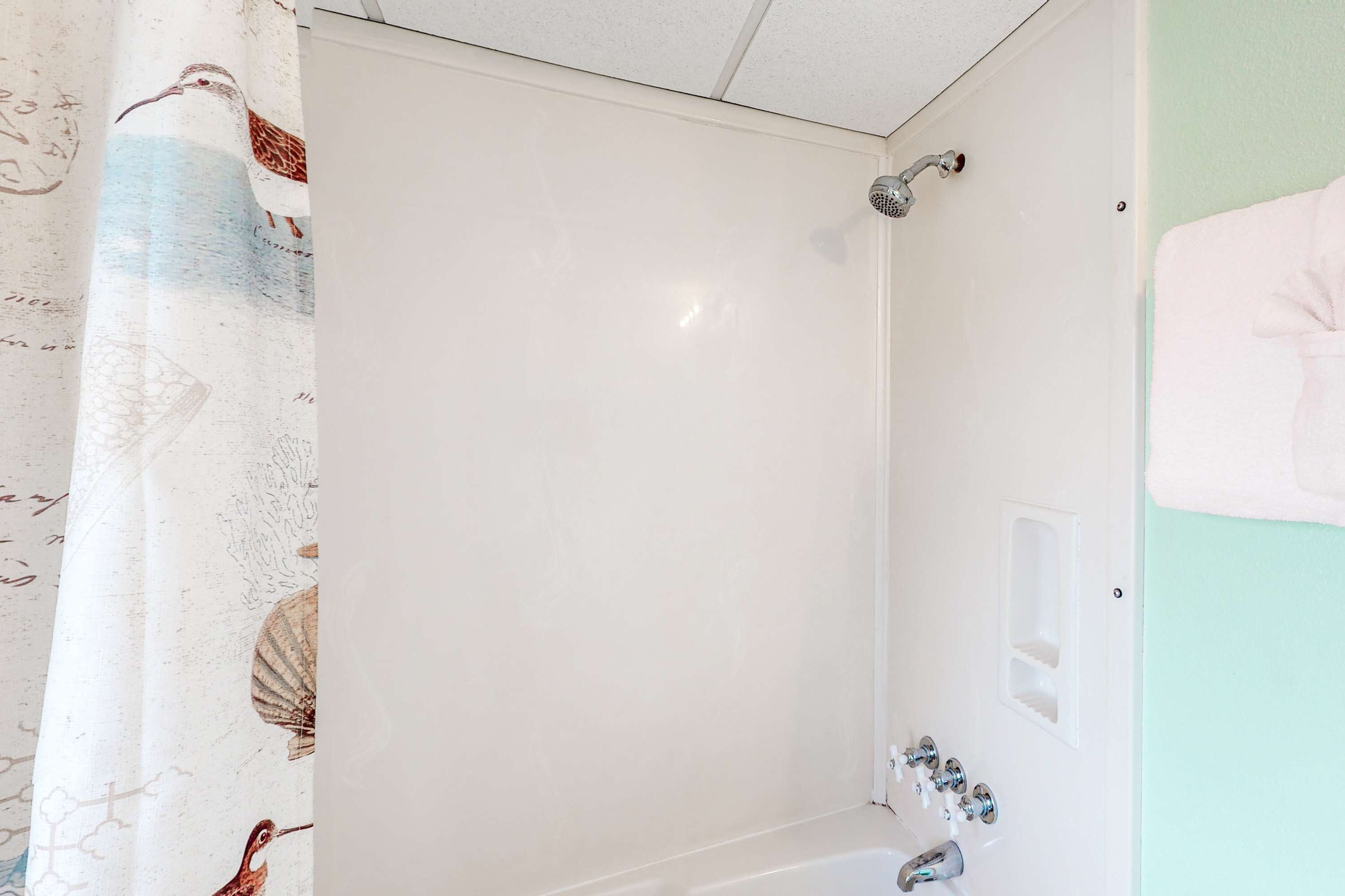 Un baño con ducha, perchero y cortina decorada con motivos de pájaros.