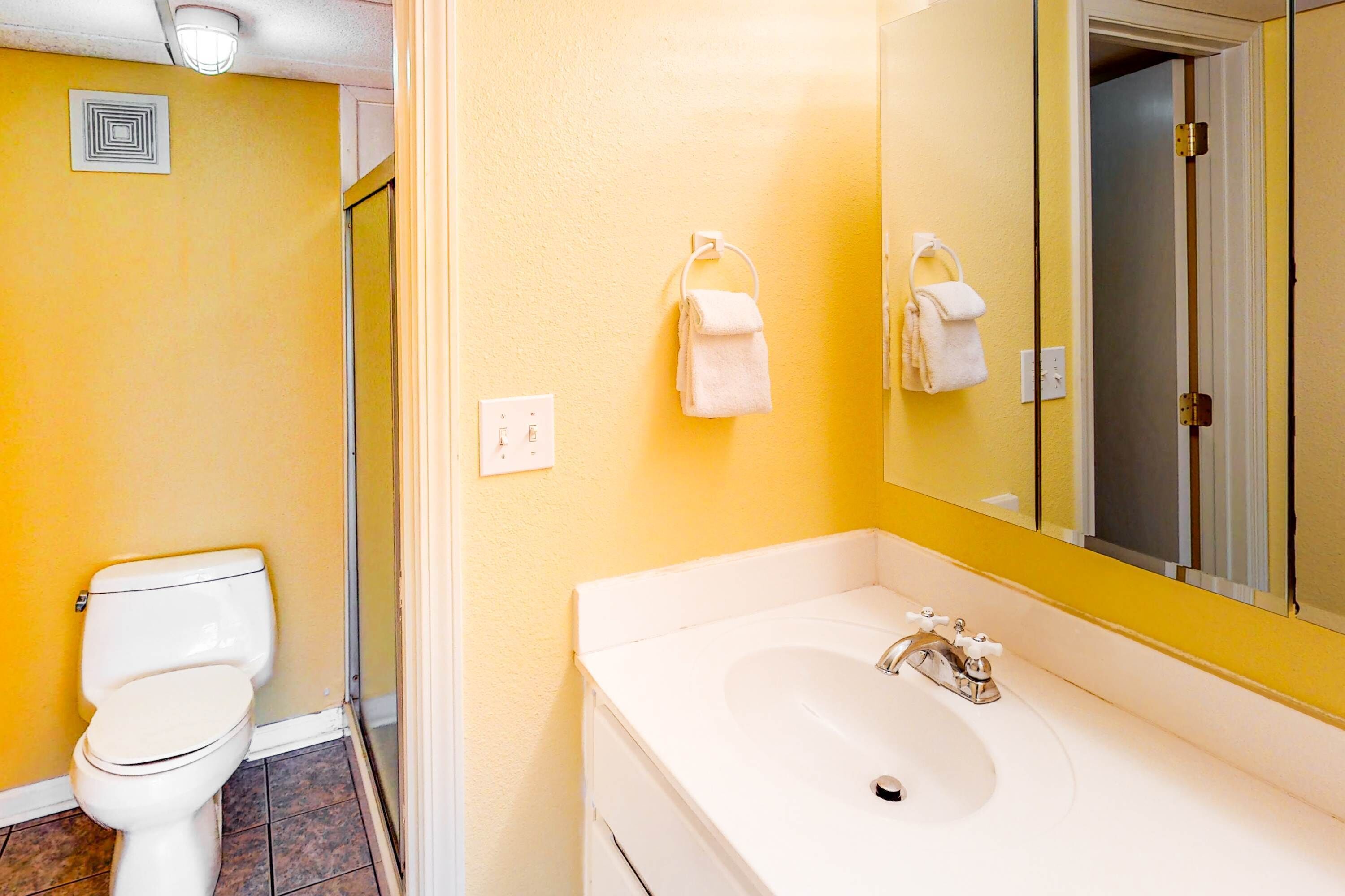 A bathroom with a white toilet, a sink, and a mirror.
