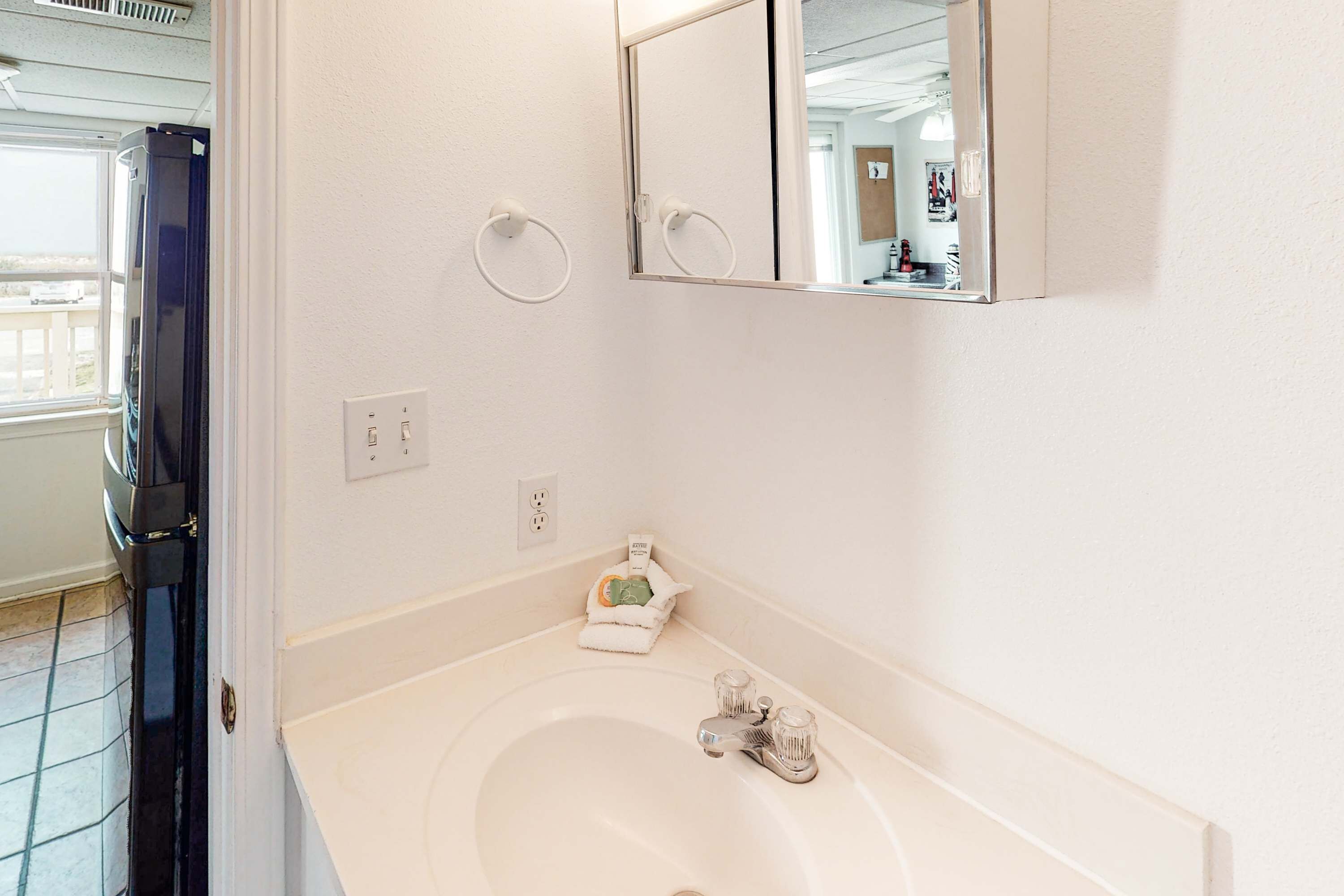 A bathroom with a white sink, a mirror, and a towel rack.